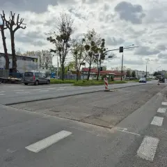 Droga w Opolu z widocznymi pracami drogowymi, samochodami i drzewami.