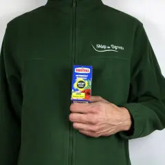 Mężczyzna w zielonej bluzie trzyma opakowanie środka ochrony roślin Saprol.
