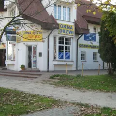 Budynek z żółtymi banerami "OKNA DRZWI" i "DRZWI PARAPETY" w Olsztynie.
