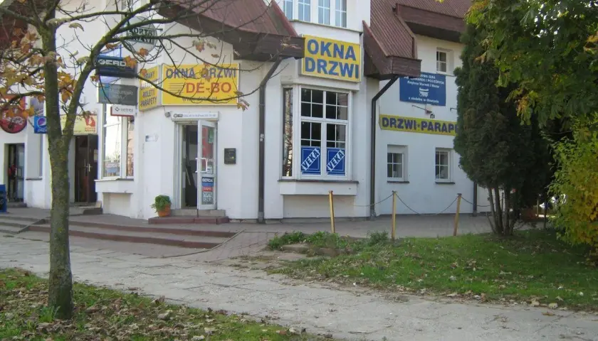Budynek z żółtymi banerami "OKNA DRZWI" i "DRZWI PARAPETY" w Olsztynie.